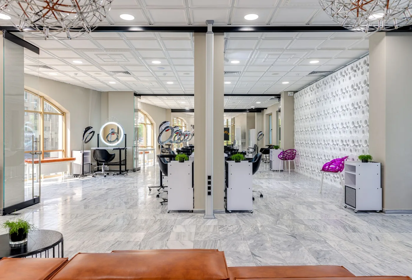 Interior luminoso de un salón de belleza con espejos y estaciones de atención
